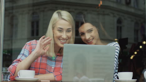 two attractive friends using laptop and having a video call