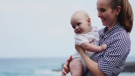 amid the sounds of the sea, the mother playfully tosses her son skyward, creating a joyful scene on the beach. a young family embraces happiness by the shore