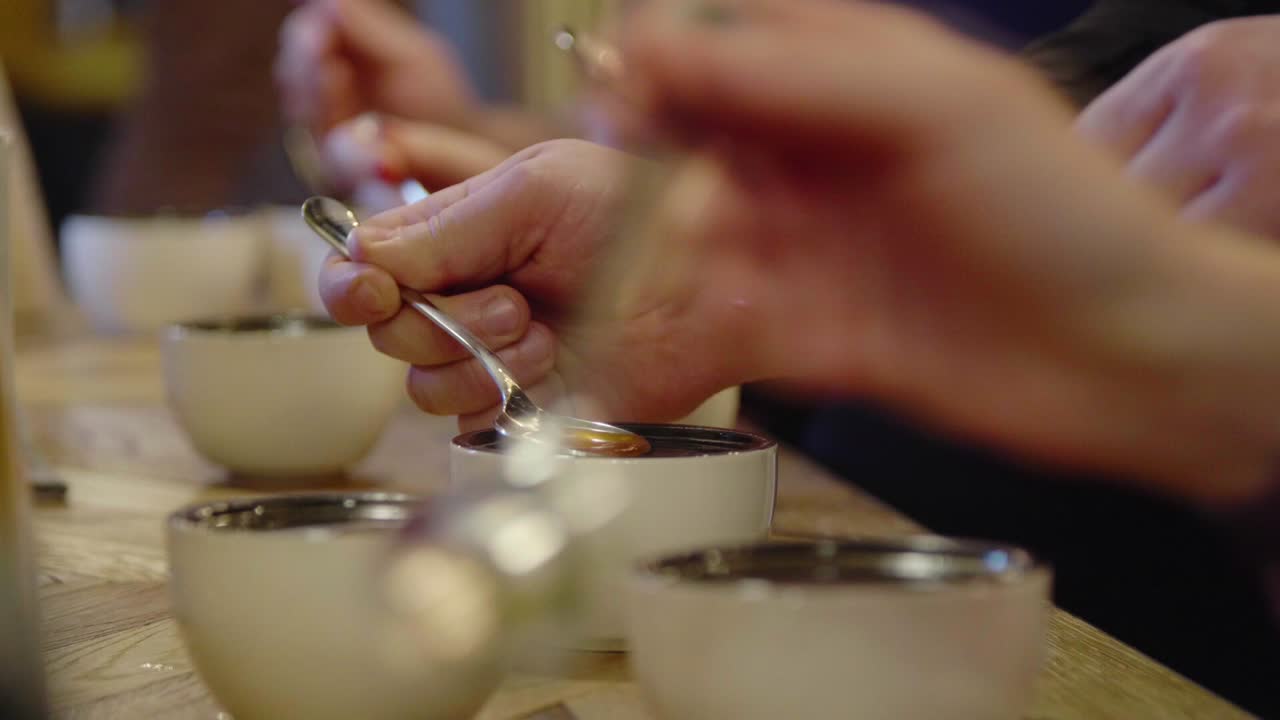 Cupping, coffee tasting, enthusiasts pour the beverage from spoon to spoon