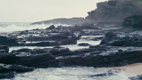 Wellen-Schlagen-Auf-Vulkangestein-Am-Sandstrand-In-Hawaii