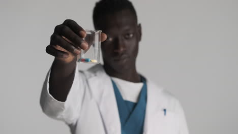 un médico afroamericano serio con un fondo gris.