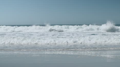 Big-waves-crash-on-the-beach,-looks-like-they-are-about-to-go-against-the-video-camera,-in-Nazare,-Portugal