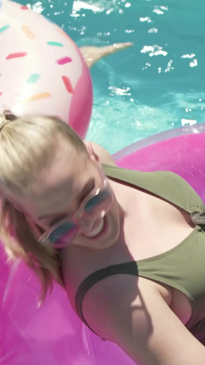 Vertical video: Reaching woman in green steadying ring at pool as child coming on donut paddling