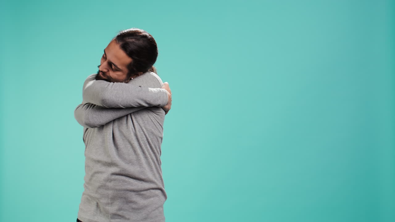 retrato de un hombre de pie en el estudio, abrazándose a sí mismo, haciendo amor propio