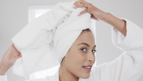 retrato de uma mulher biracial feliz usando uma toalha na cabeça no banheiro, em câmera lenta