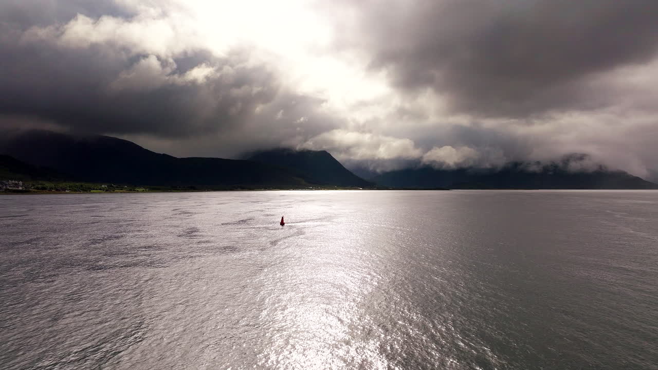 Luftbåren dolly-bevægelse mod sejlbåd ud for kysten under mørke bjerge i Sortland, Vesterålen, Norge.