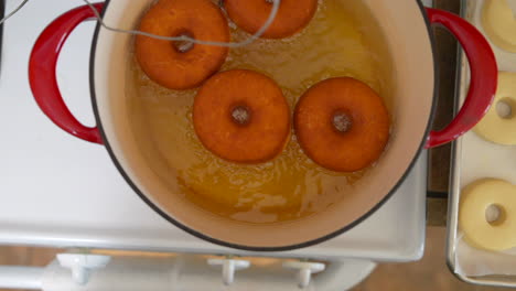 overhead view, four donuts deep fry in dutch oven oil, slow motion