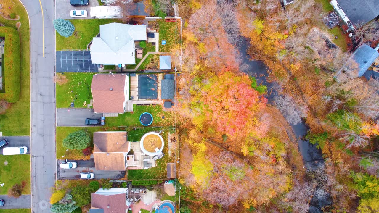 Aerial: small town during the day with trees, a river and autumn colors in the region of Estrie, Quebec, Canada, top down drone shot