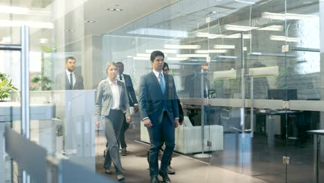 diverse team of delegates/ lawyers confidently marching through the corporate building hallway. multicultural crowd of resolute business people in stylish marble and glass offices.