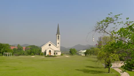 catholic style church building without a cross surrounded with green grass fields on a bright clear day