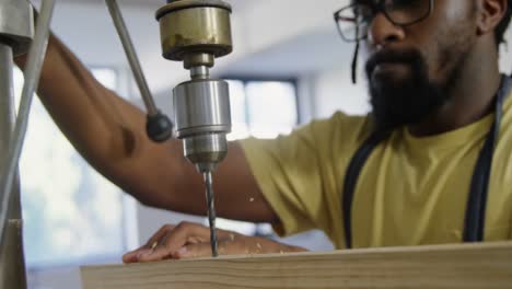 Carpenter-drilling-wooden-plank-with-machine-in-workshop-4k