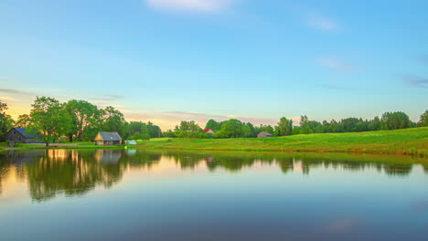 timelapse of serene pond surrounded by vibrant green fields and overcast clouds drifting by, with changing light and colours