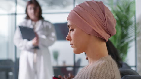 close up of young woman patient wearing headscarf being called for chemotherapy treatment for breast cancer in hospital clinic