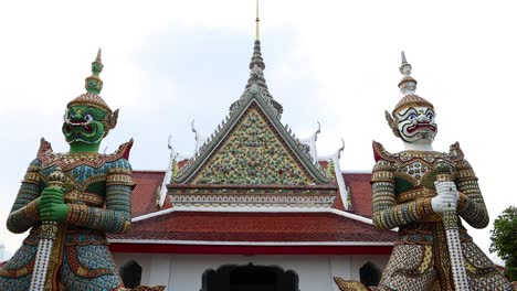 visitors approach wat arun's grand entrance statues