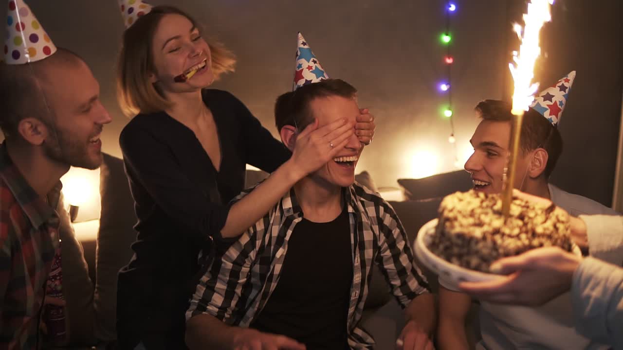 생일 파티를 축하하는 화려한 모자를 쓴 친구들, 반짝이는 막대기를 태우고 케이크를 들고 있는 놀라운 친구