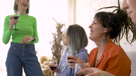 cheerful female friends drinking wine and talking during a fun party at home