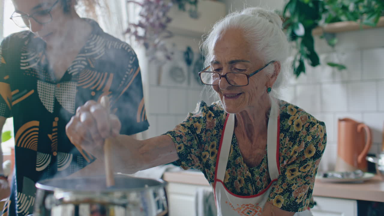 Donna anziana che mescola il cibo in una pentola fumante mentre cucina con il nipote.