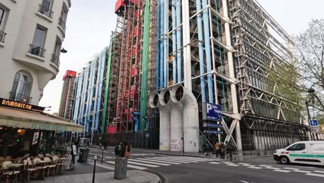 pedestrians and vehicles pass by a vibrant building.