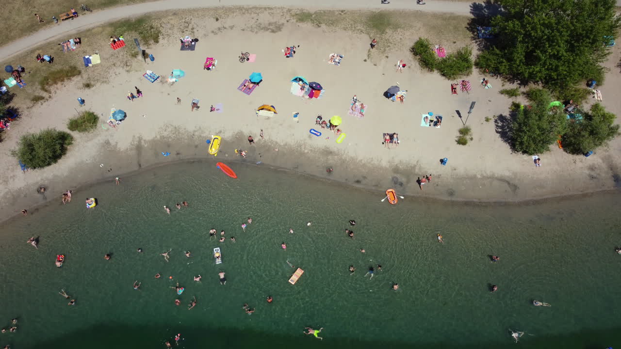 Aerial View of People Relaxing and Swimming at a Lake Beach