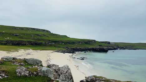 remote house by the beach with rocky coastline in port na ba, isle of mull in scotland. - wide pan shot