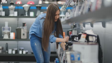 In-the-appliances-store,-the-kitchen-appliances-woman-chooses-a-blender-in-her-hands-and-considers-the-design-and-characteristics.