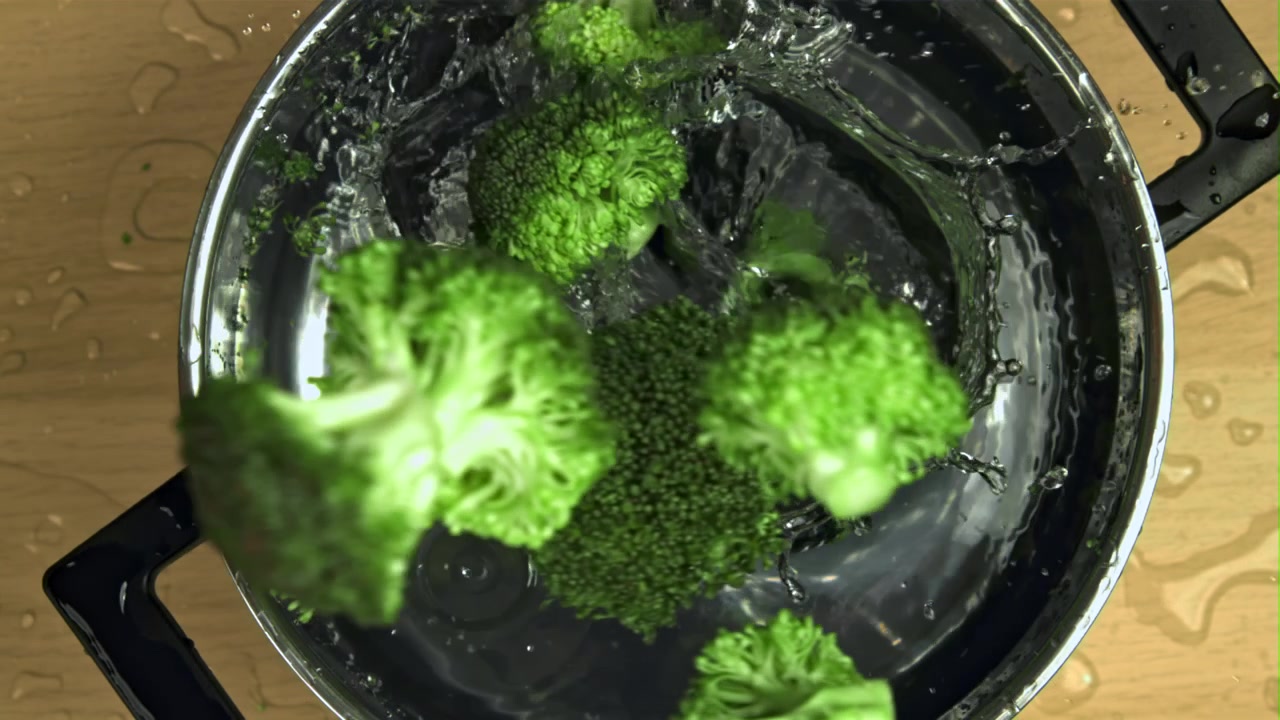 Cimette di broccoli freschi che schizzano nell'acqua in una pentola