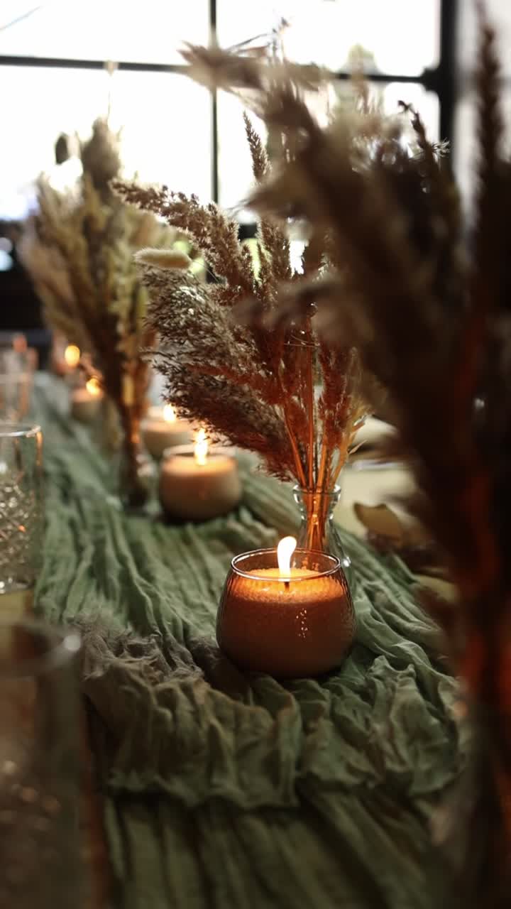 Candele calde accese ed erba della Pampa essiccata su un tavolo decorato