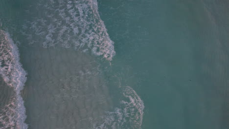 aerial top down shot of rolling waves in a crystal clear ocean in cancun, mexico