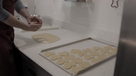 cutting out a heart-shaped butter cookie and putting it on a baking tray in an artisanal pastry shop