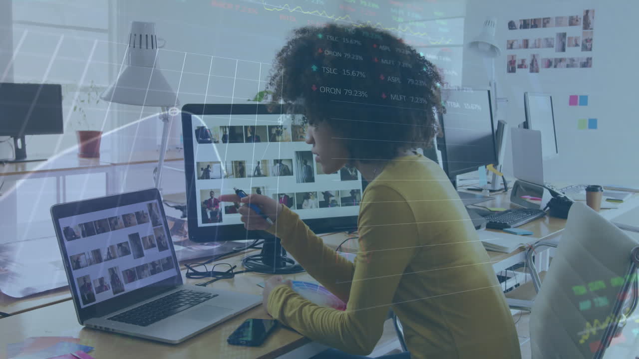 A biracial woman is working in a creative office and using a laptop