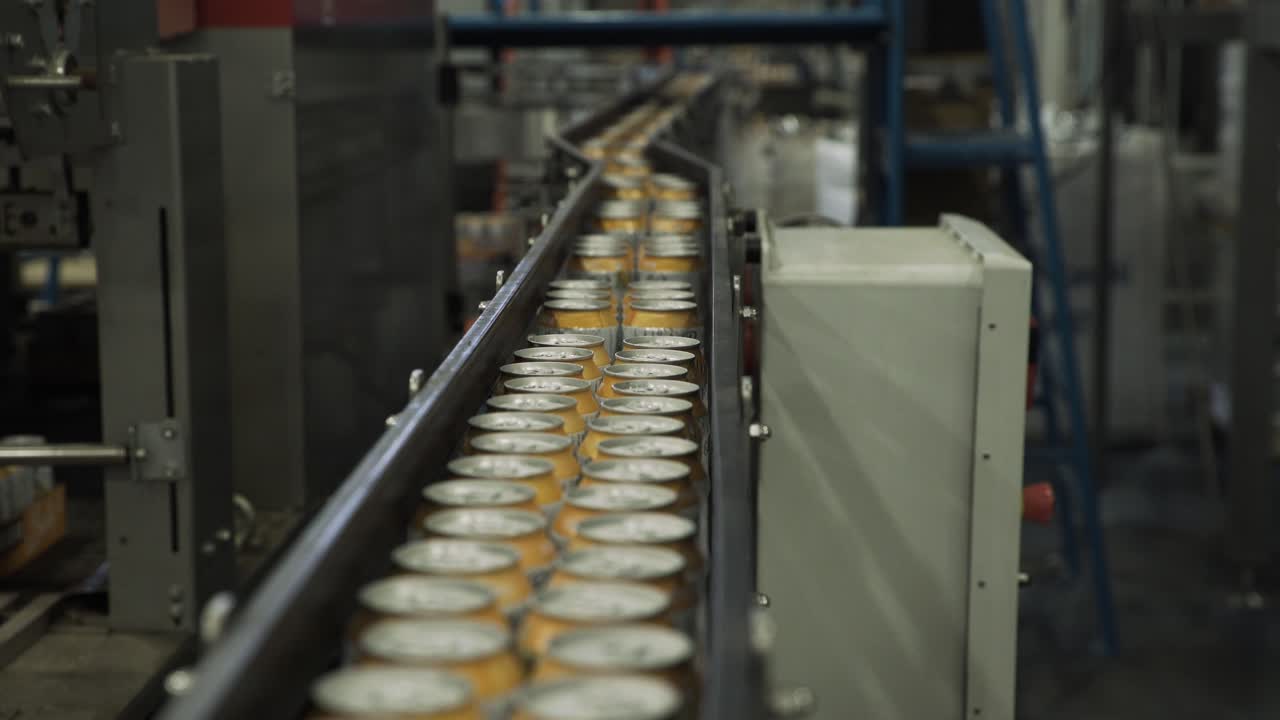 Close up of aluminium cans moving through converyor belt in packaging factory
