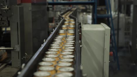 Close-up-of-aluminium-cans-moving-through-converyor-belt-in-packaging-factory