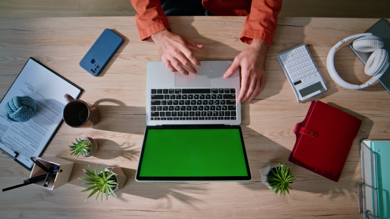 Freelancer hands browsing chroma key laptop in professional workspace top view