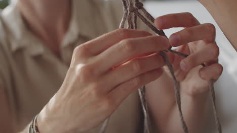 woman knotting macrame with help of female friend