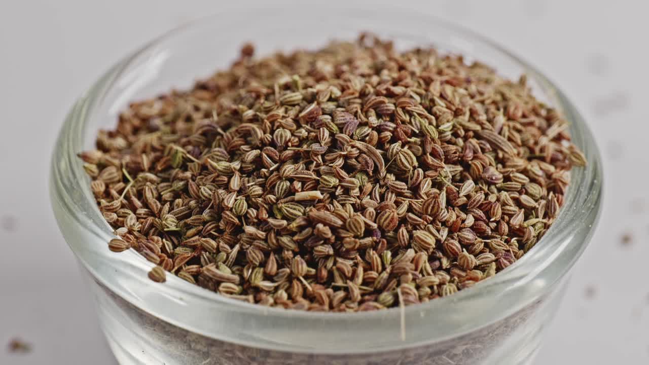 carom seeds or ajwain in small glass bowl, closeup, 4k, parallax shot.