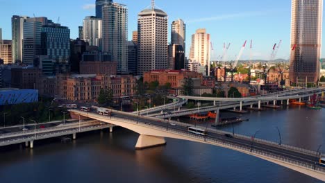 articulated buses driving across victoria bridge with brisbane cbd skyline in australia