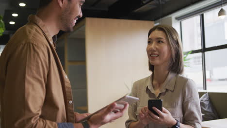 mujer de negocios asiática de pie usando una tableta digital en una oficina moderna
