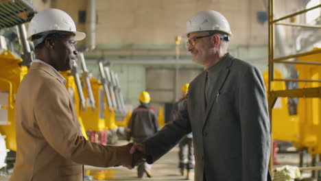 Two Engineers Shaking Hands and Speaking in Factory