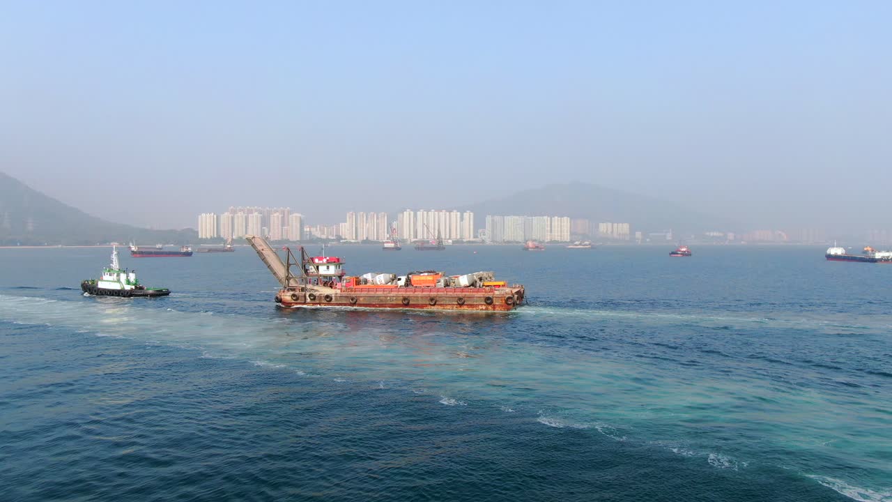 barcaza cargada con camiones hormigonera tirada al puerto por un remolcador en la bahía de hong kong, vista aérea