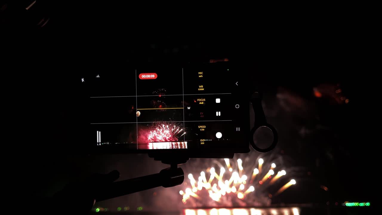 cámaras alineadas en una fila frente a una exhibición pirotécnica en una playa durante un festival de fuegos artificiales