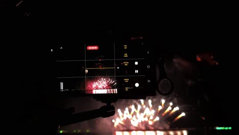 cameras lined up in a row in front of a pyrotechnic display at a beachfront during a fireworks festival