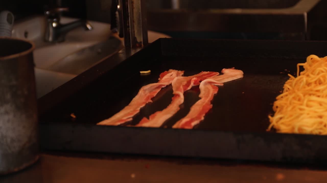 Strips of bacon cooking to go in noodles