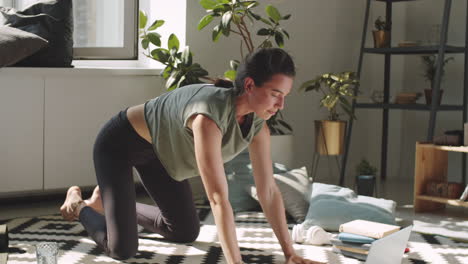 woman practicing yoga with online class on laptop