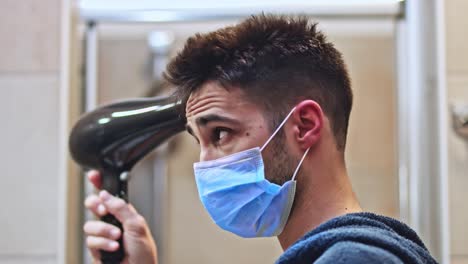 joven con una máscara protectora secándose el pelo