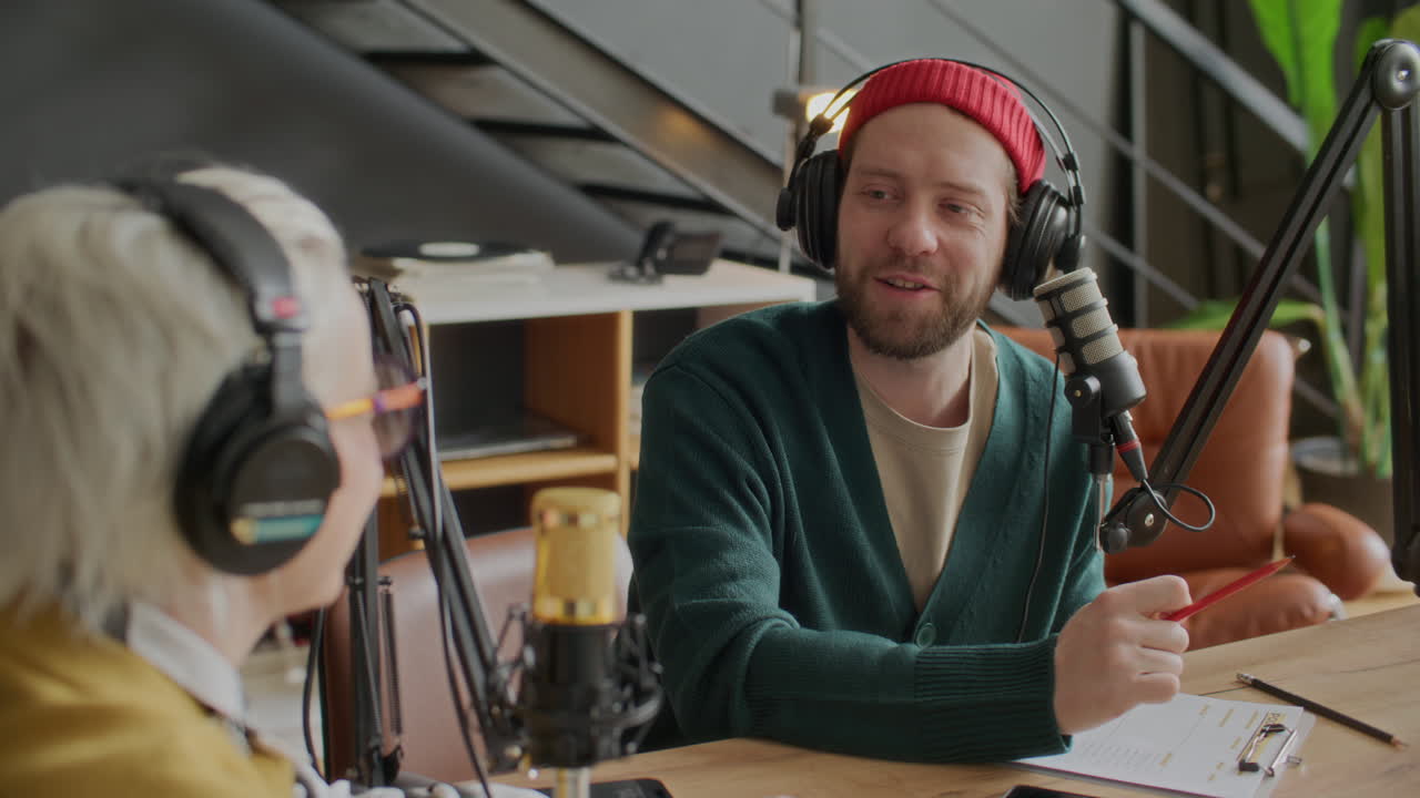 Podcaster uomo che parla con un'ospite donna durante una sessione di registrazione in studio