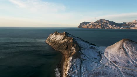 snowy mountain cliff by the ocean