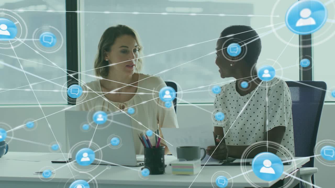 Women reviewing at desk left woman pointing laptop sparking growing blue chat network in business