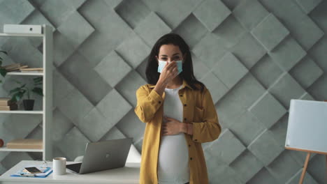 young pregnant business woman puts on a face mask