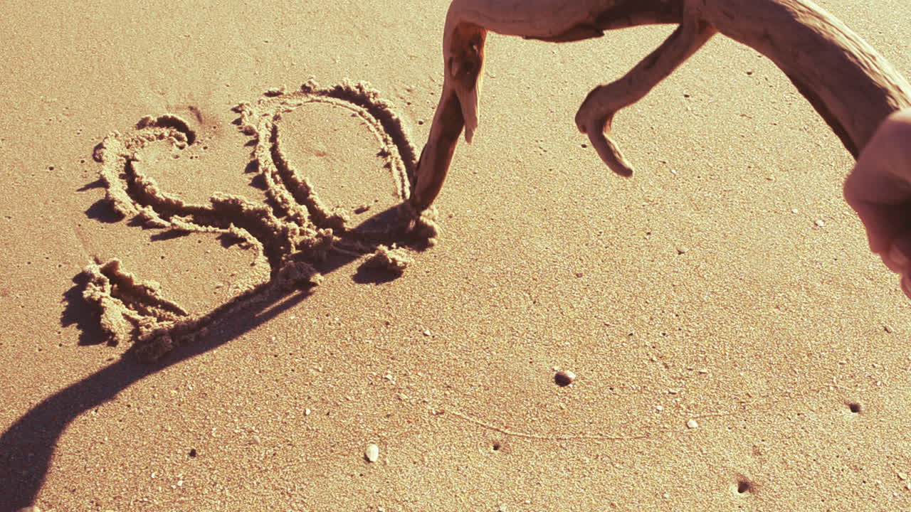 Ordet SOS i sanden. Strand. Inspelning på stranden