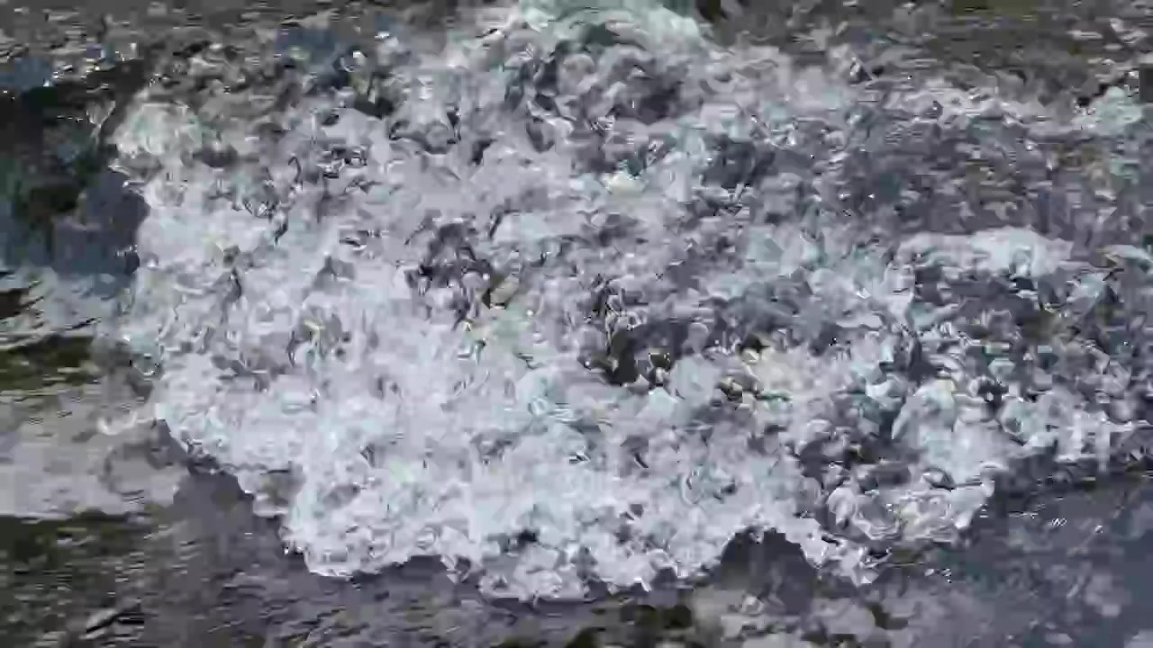 Primo piano di acqua impetuosa che scorre su rocce in un ruscello